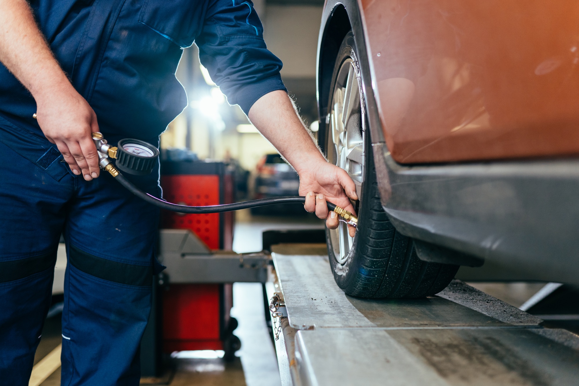Car Tire Pressure Check in the Auto Service Garage. Detail of inflating tire and checking